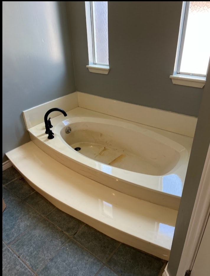 Worn and discolored cultured marble bathtub before being refinished by Dallas bathtub refinishing services